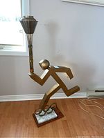 Front view of full sculpture showing runner, torch, rings, marble and wood base