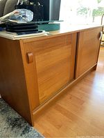 Three-quarter view of teak credenza showing sliding doors and recessed wooden handles