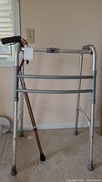 Front view of Lumex aluminum walker with padded handles and Airgo aluminum cane leaning inside the walker.