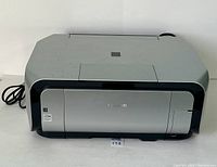Front angled view of Canon Pixma MP610 printer showing scratches on top lid and overall body condition with power cord attached.