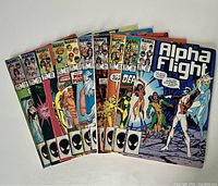 Ten Marvel Alpha Flight comic books fanned out showing covers including issues from 18 to 27 with vibrant colors and characters.