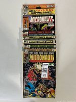 Eight Marvel Micronauts comic books stacked, showing colorful covers with Marvel Comics Group logo and Micronauts branding. Some covers advertise contests and feature characters in action poses.