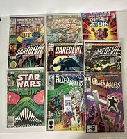 Photo showing all 9 comics laid out flat in a 3x3 grid highlighting front covers.