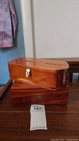 Two wooden souvenir boxes stacked, smaller box on top, showing polished wood and latch lock on smaller box.