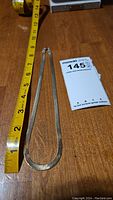 Full view of the sterling silver chain necklace with measuring tape showing about 12 inch chain length and auction lot card.