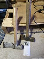 Photo of two axes with wooden handles and metal heads showing wear and rust.