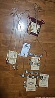 Full view of the five jewelry pieces arranged on a wooden floor showing three perfume bottle necklaces with chains and two sets of cameo jewelry.
