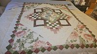 Full view of the floral patchwork quilt with diamond centerpiece and floral border.