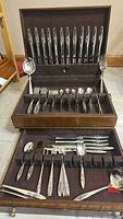 Open wood case showing upper drawer with knives and middle tray with tablespoons and forks