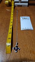 Full view of necklace with ruler showing chain length approx 15.5 inches.