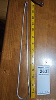 Full length of flat silver chain displayed next to a measuring tape showing length of about 14 inches.