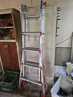 Three-section aluminum telescoping ladder in closed configuration leaning against wall