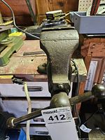 Front view of the heavy duty metal bench vise mounted on a workbench showing the screw handle and the vise jaws.