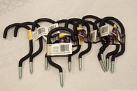 All 10 black foam coated screw in hooks with attached packaging labels shown in a group on a flat surface.