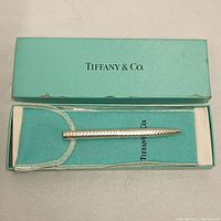 Tiffany & Co. silver pen displayed in original blue box and velvet pouch, highlighting brand and packaging.