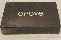 Photo of Opove M3 Pro massage gun box sealed in factory shrink wrap, black box with white Opove logo.