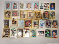 Overall collection of about 31 sports cards showing various players from hockey, baseball, and football with some cards in protective sleeves.