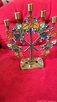 Front view of colorful brass and enamel menorah with detailed leaves and five candle holders