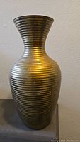 Front view of tall ribbed brass vase showing flared neck and rounded body.