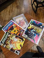 Twelve assorted comic books laid out on wooden surface including Supreme, Xecutor, and Freestar among others.