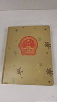 Gold hardcover stamp album with embossed Chinese national emblem and decorative motifs