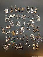 Full layout of all assorted pierced earrings on black background showing variety of styles and materials.