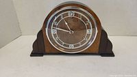 Front view of the electric vintage mantle clock with wooden body and glass face showing clock hands and numbers.