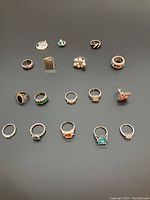 Overhead view of 13 silver-tone costume rings in various stone colors and designs