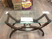 Top view of the sofa table showing the clear glass rectangular top and the dark wooden base with oval and straight design elements.