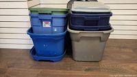 Side view of stacked storage totes showing blue, gray, and green lids.