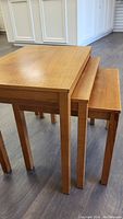 Set of three teak nesting tables nested together showing legs and tabletops
