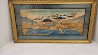 Full view of the framed vintage Asian carved wood picture depicting a lake scene with boats, houses, and trees.