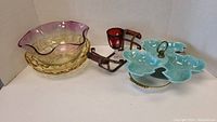 Photo showing frilled glass bowl with pink rim, yellow bowl, blue leaf motif candy dish on gold stand, and red glass candle holders