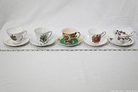 Five English fine bone china teacup and saucer sets arranged in a row showcasing each cup and attached saucer from left to right.