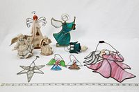 All ceramic and stained glass angels along with star ornament arranged on white background with ruler for size reference.