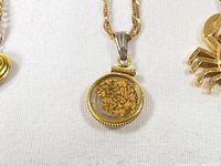 Front view of circular glass pendant filled with gold flakes and braided gold chain