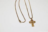 Rolled gold Celtic cross pendant hanging on matching chain displayed flat
