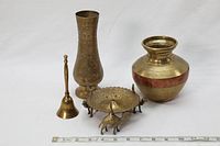 Photo showing all five brass items including the bell, two vases, and incense burner supported by brass camels with a ruler for scale.