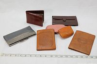 Photo showing the seven vintage leather wallets and coin purse laid out with a ruler for scale.