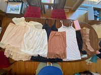 Overview photo showing the full collection of vintage lingerie items laid flat on table, including slips, blouse, and stockings.