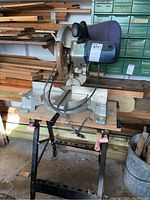 Mastercraft 10-inch compound mitre saw mounted on a metal stand, showing blade and handle from side angle in workshop environment.