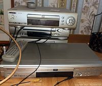 Four media players stacked and arranged, showing front panel details and remote control