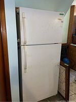 White Frigidaire refrigerator showing front view with upper freezer door and lower refrigerator door. Visible wear and dirt on the surface.