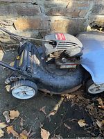 Side angle view of the Yard Machines lawn mower showing wheels, deck, and handlebar.
