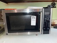 General Electric microwave oven on countertop showing front and control panel with keypad and digital screen, stainless steel finish.