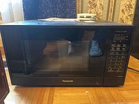 Front view of Panasonic microwave on floor showing front door with reflection and visible control panel.