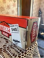 Photo of red and beige cardboard box with Expert Grill branding and maxsold auction label