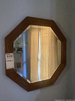 Front view of the octagonal mirror with oak frame and beveled edges reflecting a curtain.