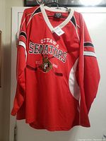 Front view of red Ottawa Senators hockey jersey featuring team name, established date, and logo.