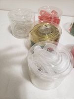 Image showing several rolls of decorative string lights in clear plastic packaging, colors include red and white with a gold roll in the back.